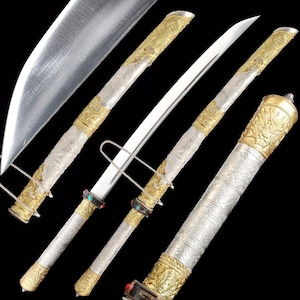 Peut inclure: Une épée ornée avec une lame argentée et une poignée décorative. La poignée et le fourreau présentent des accents dorés et argentés avec des motifs complexes et des ornements aux couleurs de bijoux. L'épée est présentée sur fond noir.