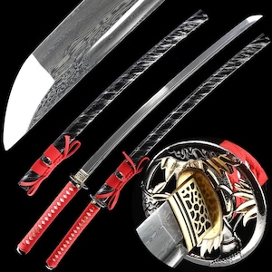 Op de afbeelding: Een bovenaanzicht van twee Japanse katana-zwaarden. De bladen zijn zilverkleurig met een patroon. De handvatten zijn rood met een ruitpatroon. De zwaardbeschermers zijn zilver en goud met ingewikkelde ontwerpen. Rode linten zijn om de handvatten gebonden.