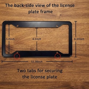 Op de afbeelding: Zwart kentekenplaatraam met afmetingen. Het frame is 31,19 cm lang, 16,18 cm hoog en 10,41 cm breed. De tekst luidt "De achterkant van het kentekenplaatraam" en "Twee lipjes om de kentekenplaat te bevestigen."