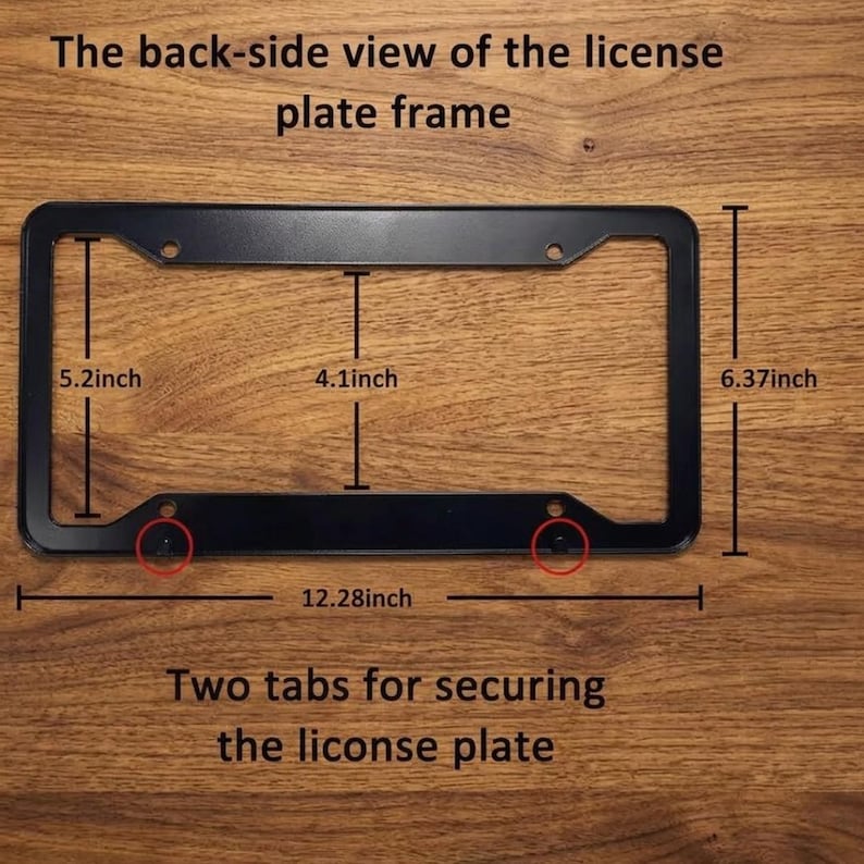Op de afbeelding: Zwart kentekenplaatraam met afmetingen. Het frame is 31,19 cm lang, 16,18 cm hoog en 10,41 cm breed. De tekst luidt "De achterkant van het kentekenplaatraam" en "Twee lipjes om de kentekenplaat te bevestigen."