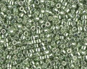 May include: A large quantity of small, round, green glass beads with a metallic sheen.