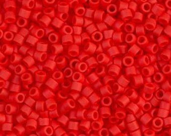May include: A close-up view of a large quantity of small, red, round seed beads. The beads are opaque and have a smooth, shiny finish.