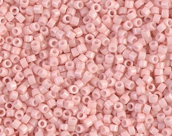 May include: A close-up view of a large quantity of small, pale pink, square-shaped beads. The beads have a hole in the center and are made of glass.
