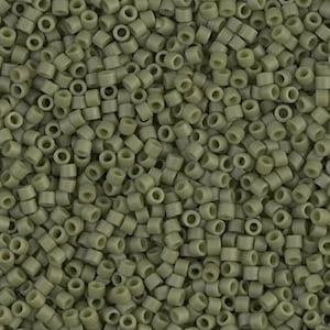 May include: A close-up view of a large quantity of small, round, olive green seed beads. The beads are arranged in a random pattern, creating a textured surface.