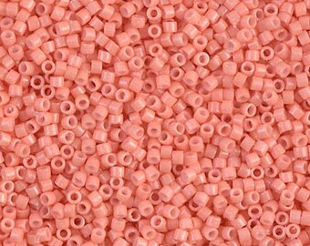 May include: A close-up image of a large quantity of small, round, light pink beads. The beads are made of plastic and have a smooth, shiny finish.