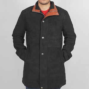 May include: A black suede coat with a contrasting brown leather collar and a red interior. The coat features a button-up front, two front pockets, and a warm, textured lining. The coat is designed for cold weather.