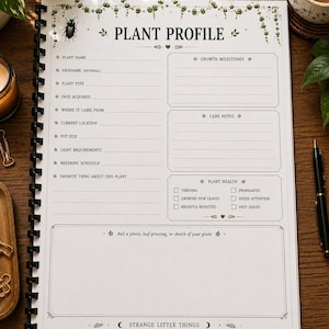 An open spiral-bound notebook displaying a "Plant Profile" page with sections for plant name, date acquired, care notes, and plant health, on a wooden surface with a candle and plants.