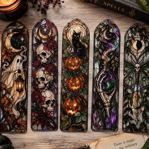 May include: Five vertical bookmarks featuring stained glass style illustrations. Designs include a ghost with a lantern, three skulls with red flowers, a black cat with three jack-o'-lanterns, a skeletal hand holding a glowing potion, and a moth with a skull.