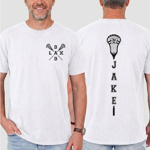 May include: White t-shirt with a black lacrosse stick graphic and the text "DAD LAX D" on the front. The back of the shirt features a lacrosse stick with the number "17" and the name "JAKE" printed vertically.