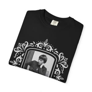 Puede incluir: Camiseta negra con un retrato en blanco y negro de una mujer en un marco blanco decorativo. El marco tiene un dise&ntilde;o floral. La camiseta tiene cuello redondo y una etiqueta que dice "Comfort Colors".