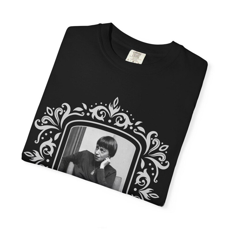 Puede incluir: Camiseta negra con un retrato en blanco y negro de una mujer en un marco blanco decorativo. El marco tiene un dise&ntilde;o floral. La camiseta tiene cuello redondo y una etiqueta que dice "Comfort Colors".