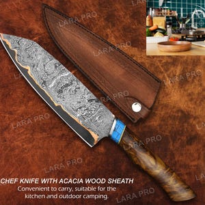 May include: Chef knife with acacia wood handle and sheath. The blade has a unique patterned design with a blue and gold accent on the handle. The knife is designed for kitchen and outdoor use.