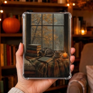 Könnte beinhalten: Eine transparente Tablet-Schutzhülle mit einem aufgedruckten Bild einer gemütlichen Fensterszene, die eine schlafende getigerte Katze, einen Bücherstapel, ein offenes Buch, eine dampfende Tasse und eine brennende Kerze auf einer karierten Decke zeigt.