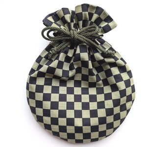May include: A drawstring pouch featuring a repeating checkered pattern in black and muted olive green. The bag is cinched at the top with a thick, braided olive green cord tied into a bow, creating a gathered, rounded shape at the opening.