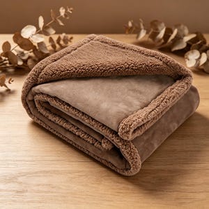 May include: A folded, brown blanket with a plush, sherpa-like trim. The blanket is a solid color and appears soft and warm. The blanket is folded neatly, showcasing the contrasting textures of the fabric.