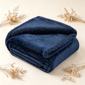 May include: A folded navy blue blanket with a plush, velvety texture. The blanket has a soft, sherpa-lined border. The blanket is made of a soft, comfortable material.