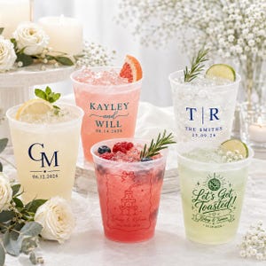 May include: Five clear plastic cups filled with ice and beverages, each featuring custom printed text and graphics. Designs include names, initials, dates, a champagne tower, and a disco ball with the text Let's Get Toasted.