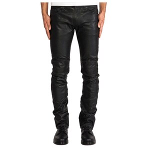 Puede incluir: Pantalones de cuero negro con aspecto texturizado. Los pantalones tienen un corte ajustado y presentan un diseño fruncido en las rodillas y los tobillos. Se combinan con zapatos de cuero negro.