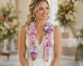 May include: A white sleeveless dress with a deep V-neckline and intricate lace detailing, worn with a long floral garland featuring purple and pink orchids, roses, and small blossoms, finished with two white fabric tassels hanging at the front.
