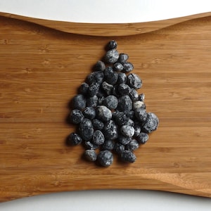 May include: A collection of black and white stones arranged in a tree shape on a wooden tray.