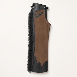 May include: A pair of chaps featuring a brown suede central panel and black crocodile-embossed leather trim. The outer edge is adorned with long black fringe, and the waistband includes a silver-toned metal buckle closure at the top.