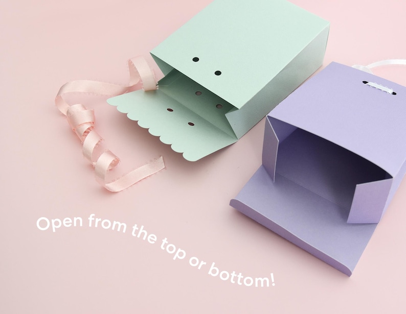 May include: Two pastel-colored gift boxes, one mint green and one lavender, are open on a pink surface. A pink ribbon is curled near the green box. The text "Open from the top or bottom!" is visible.