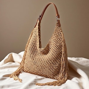 May include: A beige woven shoulder bag with a brown leather strap and fringe detailing. The bag has a large, open design and a single strap. The fringe hangs from the sides of the bag, adding a decorative element.