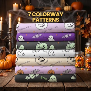 May include: A stack of seven folded fabric bolts featuring Halloween patterns including ghosts, bats, and jack-o'-lanterns in various colors like purple, black, white, and orange. The text 7 COLORWAY PATTERNS is printed above the fabric stack.