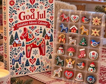 May include: A rectangular God Jul Dalahäst Advent Calendar box featuring a red Dala horse illustration and floral patterns, paired with a clear plastic tray containing twenty-four small, hand-painted ceramic ornaments in various festive shapes.