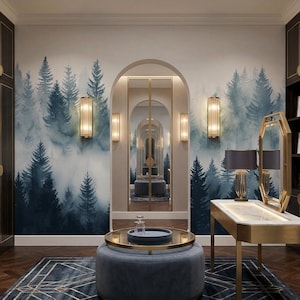 May include: A luxurious walk-in closet with dark wood cabinetry and a forest mural. A gold-framed mirror and a table with a lamp are in the center. A blue ottoman with a gold tray sits on a geometric rug. The closet is well-lit.