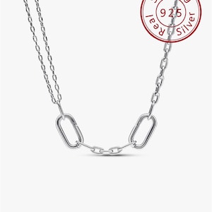 Può includere: Una collana d'argento con una catena e due maglie ovali allungate. La collana è realizzata in argento sterling, come indicato dal timbro rosso con la scritta "Sterling 925 Real Silver". La collana è esposta su sfondo bianco.