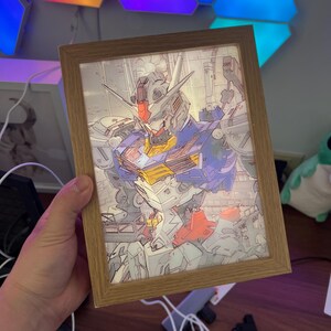 Puede incluir: Ilustraci&oacute;n enmarcada de un robot en tonos azules, amarillos, rojos y grises. La obra de arte est&aacute; en un marco de madera. El robot es muy detallado con componentes mec&aacute;nicos.