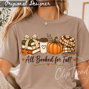 Woman wearing All Booked for Fall shirt featuring stacked books, coffee cup, pumpkin, bow and cozy plaid scarf autumn illustration.