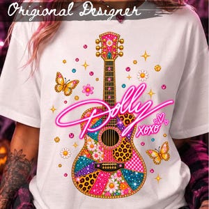 May include: A white t-shirt featuring a central graphic of an acoustic guitar decorated with colorful patterns including leopard print, floral designs, and glittery textures. The text Dolly XOXO is written in a bright neon pink script across the guitar.