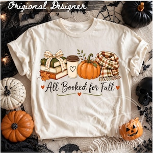 All Booked for Fall PNG displayed on a cream shirt with books, coffee, pumpkin and plaid scarf in a cozy Halloween themed room.