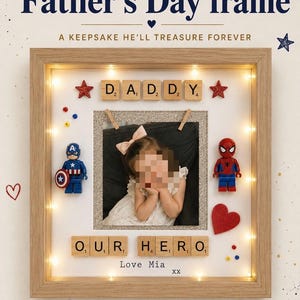 May include: A wooden Father's Day frame with the text "My Hero" and "Father's Day frame". The frame includes a photo, decorative elements, and the words "DADDY" and "OUR HERO". It has warm LED lights.
