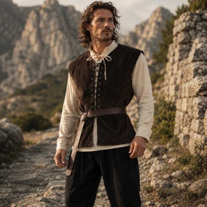 May include: A dark brown suede vest featuring a front lace-up closure with light-colored ties, worn over a long-sleeved cream-colored shirt. A wide brown leather belt is cinched around the waist, paired with loose-fitting black trousers.
