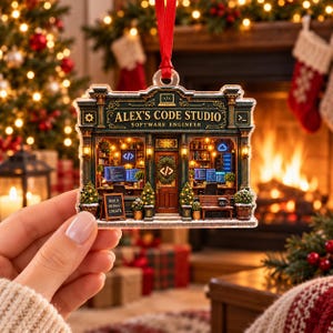 May include: A flat, rectangular acrylic ornament featuring a detailed illustration of a storefront labeled 'ALEX'S CODE STUDIO SOFTWARE ENGINEER'. The design includes computer screens, a wooden bench, and a sign reading 'BUILD DEBUG CREATE'.