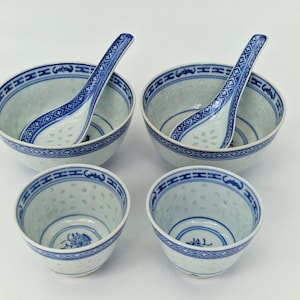 May include: A set of four white and blue porcelain bowls and spoons. Two larger bowls each contain a blue and white spoon. Two smaller bowls are also included. The bowls and spoons have a blue geometric border design.