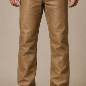 May include: Tan leather trousers with a classic five-pocket design. The trousers have a straight leg cut and are worn with dark brown leather boots. The image includes the text "Swipe up for filters".