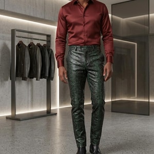 Puede incluir: Una camisa burdeos combinada con pantalones verdes con estampado de serpiente y botas negras. El atuendo se exhibe en un entorno minorista moderno, con chaquetas de cuero en el fondo.