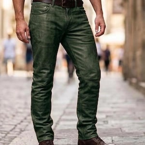 Op de afbeelding: Groene leren broek met een bruine leren riem en bruine laarzen. De broek heeft een distressed look en een klassiek ontwerp met vijf zakken. De riem heeft een zilveren gesp. De laarzen zijn met veters.