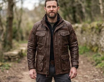 Könnte beinhalten: Eine braune Leder-Feldjacke mit mehreren Utility-Taschen, einem hohen Kragen und einem Reißverschluss. Im Brustbereich befindet sich ein rechteckiger Aufnäher mit dem in schwarzem Garn gestickten Wort SURVIVE. Die Jacke hat lange Ärmel mit Reißverschlussfächern und verstellbaren Bündchen.