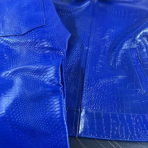 Blå krokodilpräglad skinnjacka och ormtryckta långa shorts i kohud, set med exotiskt reptilmönster i biker-outfit, redo att skickas