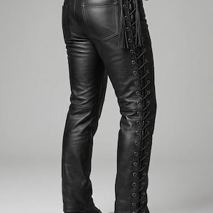 Könnte beinhalten: Schwarze Lederhose mit Schnürdetails an der Seite. Die Hose hat ein klassisches Fünf-Taschen-Design und einen Bund mit Gürtelschlaufen. Die Schnürung verleiht der Hose einen einzigartigen, kantigen Stil. Die Hose wird mit schwarzen Stiefeln kombiniert.