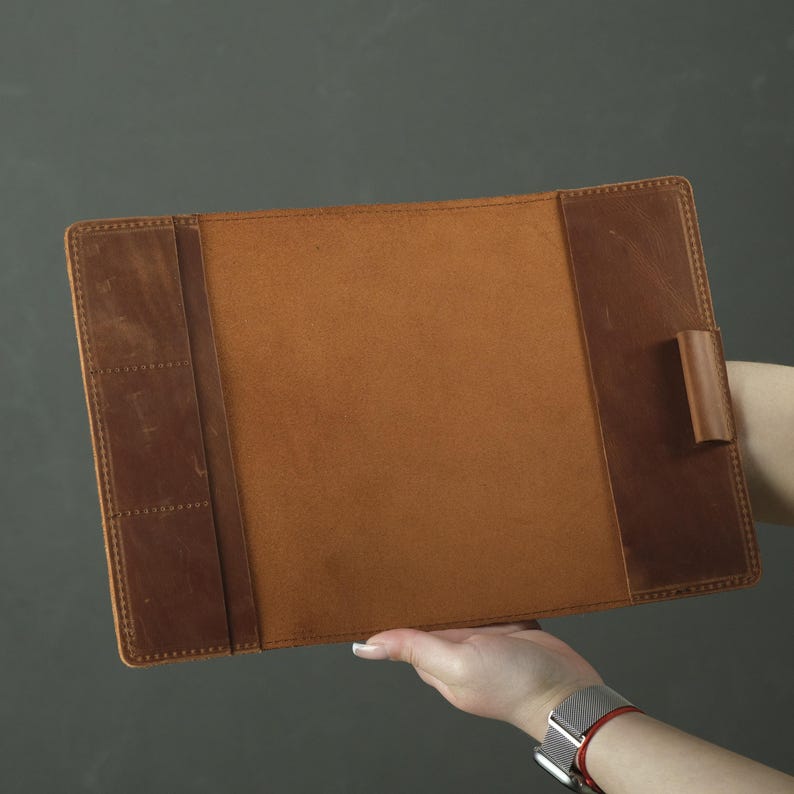 May include: A rectangular brown leather document holder featuring a smooth central panel, a left-side section with three vertical slots for cards or small items, and a single leather pen loop attached to the right-side interior panel.