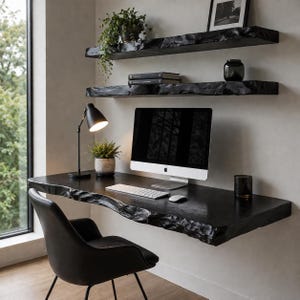 Puede incluir: Un moderno espacio de oficina en casa con un escritorio negro con borde natural, una silla negra y un ordenador. El escritorio está montado en la pared, con estantes flotantes encima. Una lámpara de escritorio negra y plantas en macetas completan la decoración. El escritorio mide unos 150 cm de largo.