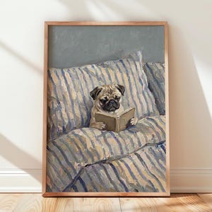 May include: A framed wall art print featuring an oil painting of a fawn-coloured pug sitting upright on a bed with blue and white striped bedding. The pug is holding an open book with its front paws, looking down at the pages against a grey background.