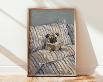 May include: A framed wall art print featuring an oil painting of a fawn-colored pug sitting upright on a bed with blue and white striped bedding. The pug is holding an open book with its front paws, looking down at the pages against a gray background.