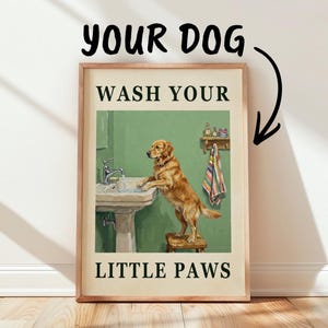 Puede incluir: Una lámina enmarcada que muestra a un golden retriever de pie sobre un taburete de madera frente a un lavabo. El texto dice YOUR DOG en la parte superior con una flecha hacia abajo, y WASH YOUR LITTLE PAWS en la parte inferior en verde.